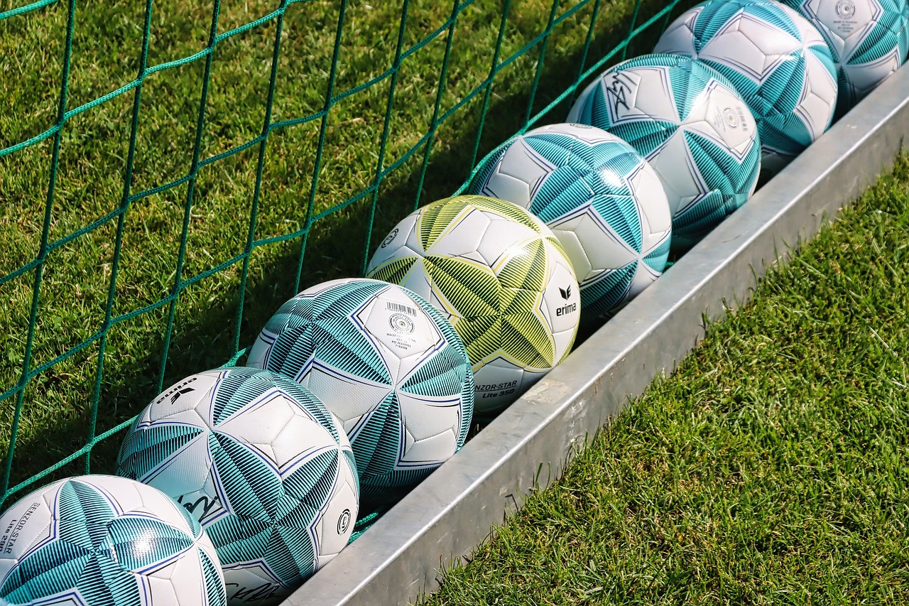 Des ballons de football alignés le long d’une barrière au bord d’une pelouse d’entraînement