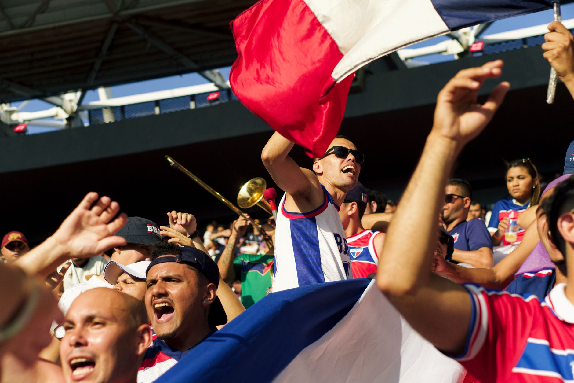 Supporters de football criant et agitant un drapeau dans les gradins d’un stade.